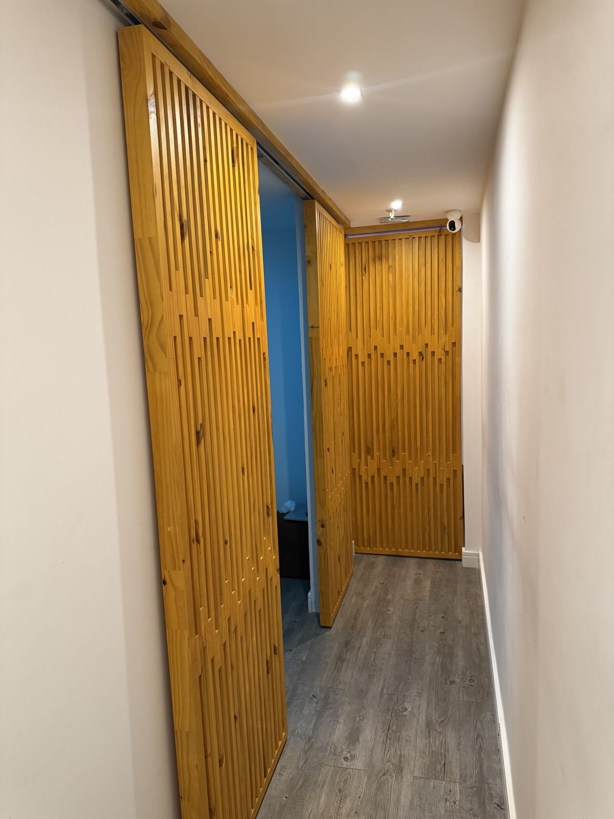 Corredor das salas com portas de correr em ripas de madeira